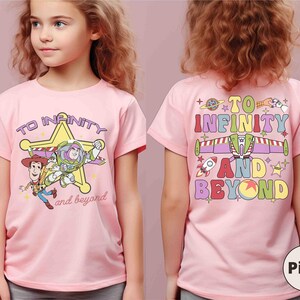 May include: Pink t-shirt featuring Woody and Buzz Lightyear from Toy Story, with the text "TO INFINITY and beyond". The back of the shirt has the text "TO INFINITY AND BEYOND" with colorful graphics.