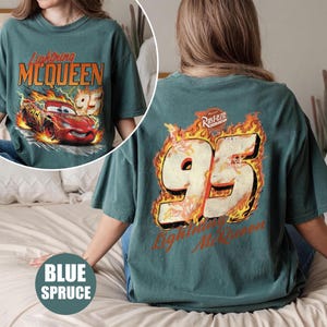 May include: Blue spruce t-shirt featuring Lightning McQueen from the movie Cars. The front graphic shows McQueen racing with the number 95. The back of the shirt displays the number 95 in flames with the text "Lightning McQueen".
