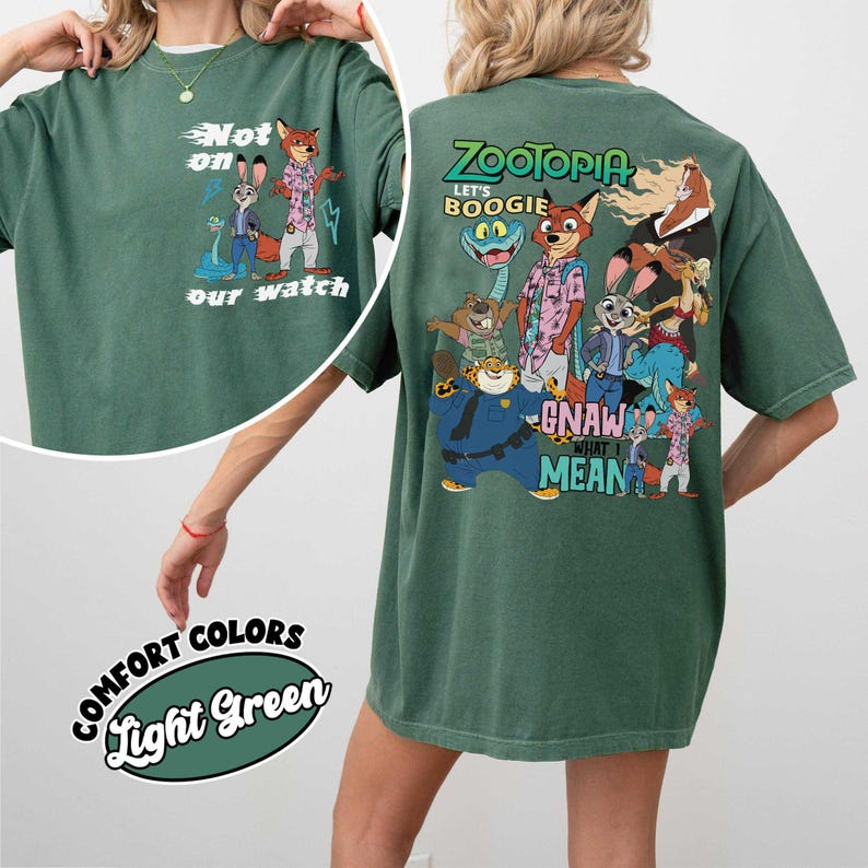 May include: Light green t-shirt featuring cartoon characters from Zootopia. The front of the shirt has the text "Not on our watch" with cartoon characters. The back of the shirt has the text "Zootopia Let's Boogie" with cartoon characters.