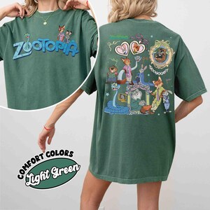 Puede incluir: Camiseta verde con la palabra "Zootopia" en azul y un dibujo animado en la parte delantera. La parte trasera de la camiseta presenta una colorida ilustraci&oacute;n de personajes de la pel&iacute;cula "Zootopia". La camiseta est&aacute; etiquetada como "Comfort Colors Light Green".