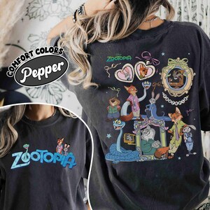 Puede incluir: Camiseta gris oscuro con la palabra "Zootopia" en azul y un gr&aacute;fico de personajes de la pel&iacute;cula de Disney. La parte trasera de la camiseta muestra un dise&ntilde;o m&aacute;s grande con varios personajes y el t&iacute;tulo de la pel&iacute;cula.