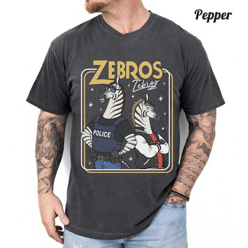 May include: Dark grey t-shirt with a cartoon graphic of two zebras. One zebra is dressed as a police officer, and the other is wearing a jacket. The text "ZEBROS + Zebras" is displayed in gold.