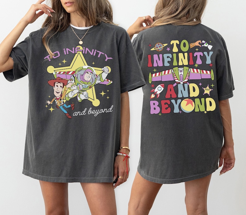 May include: Dark gray t-shirt featuring a graphic of Woody and Buzz Lightyear with the text "To Infinity and Beyond." The back of the shirt has the same phrase with a rocket, spaceship, and other colorful elements.