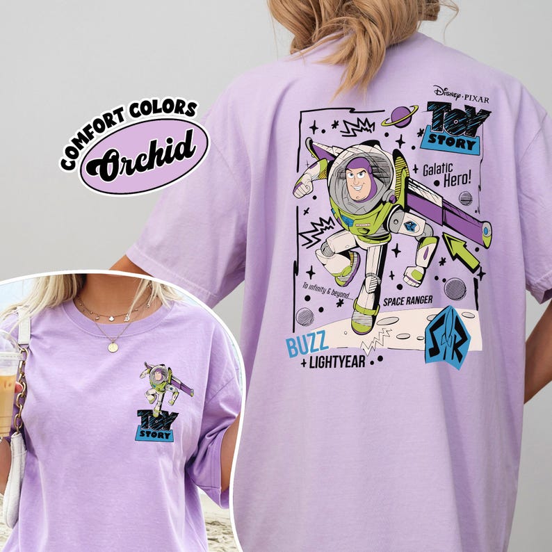 K&ouml;nnte beinhalten: Orchideenfarbenes T-Shirt mit einer Grafik von Buzz Lightyear aus Toy Story. Das Design enth&auml;lt den Text "Toy Story", "Galactic Hero!" und "Space Ranger". Das Shirt hat auch den Text "Comfort Colors" und "Orchid".