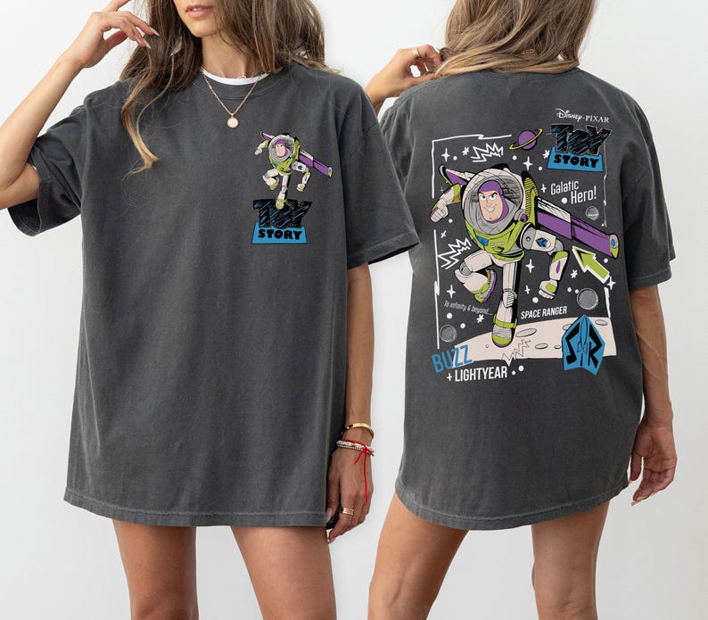 K&ouml;nnte beinhalten: Dunkelgraues T-Shirt mit einem Buzz Lightyear-Motiv aus Toy Story. Die Vorderseite zeigt ein kleines Buzz-Bild, w&auml;hrend die R&uuml;ckseite ein gr&ouml;&szlig;eres Design mit dem Text "Toy Story", "Galactic Hero!" und "Space Ranger" zeigt.