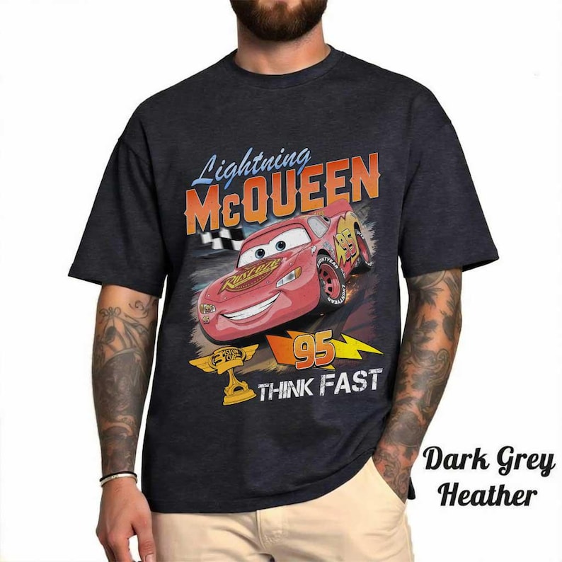 May include: Dark grey heather t-shirt featuring Lightning McQueen from the Cars movie. The graphic includes McQueen, the number 95, and the words "THINK FAST". The shirt has a classic crew neck and short sleeves.