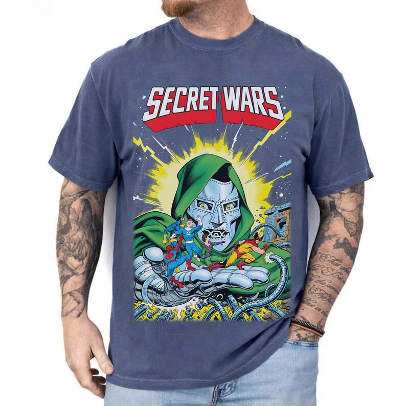 May include: Blue t-shirt featuring the text "SECRET WARS" above a comic book illustration of Doctor Doom holding several superheroes. The graphic is in bright colors with a vintage comic book style.