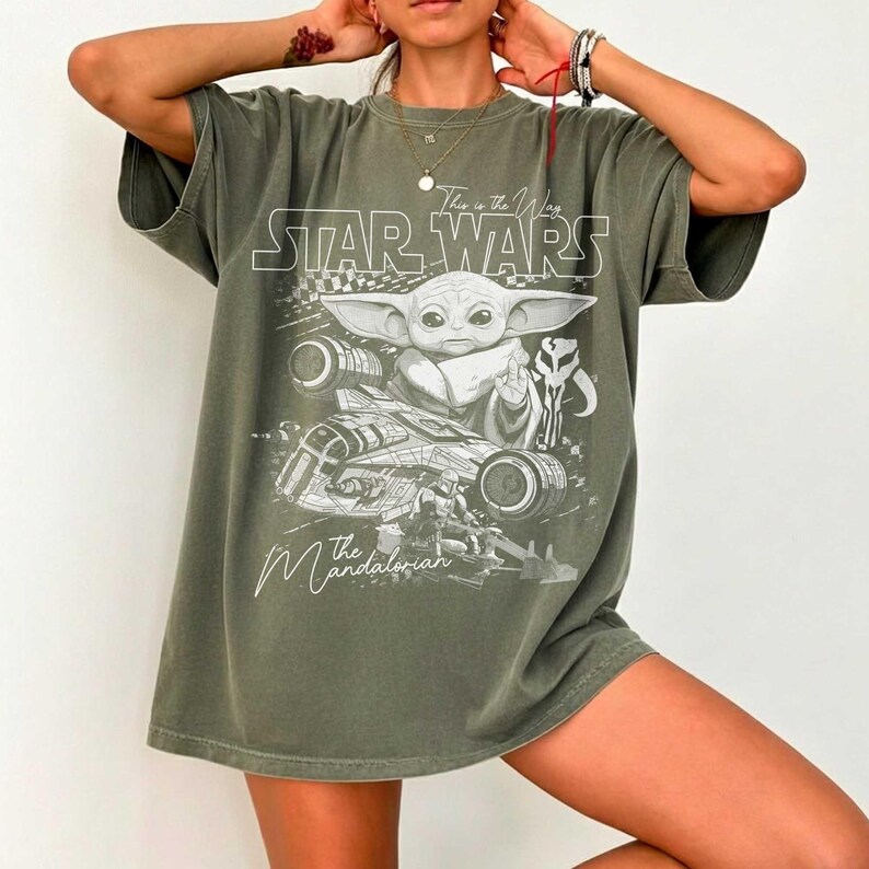 Puede incluir: Una camiseta de manga corta color verde oliva con un estampado gr&aacute;fico blanco de Grogu, una nave espacial y un casco mandaloriano. El texto dice Star Wars, This is the Way y The Mandalorian. La camiseta tiene cuello redondo y corte holgado.