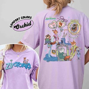 Puede incluir: Una camiseta de color lila claro con un gr&aacute;fico de personajes de la pel&iacute;cula de Disney Zootopia. La parte delantera de la camiseta tiene la palabra "Zootopia" en azul. La parte trasera de la camiseta presenta un dise&ntilde;o m&aacute;s grande con m&uacute;ltiples personajes. La camiseta est&aacute; etiquetada como "Comfort Colors Orchid".