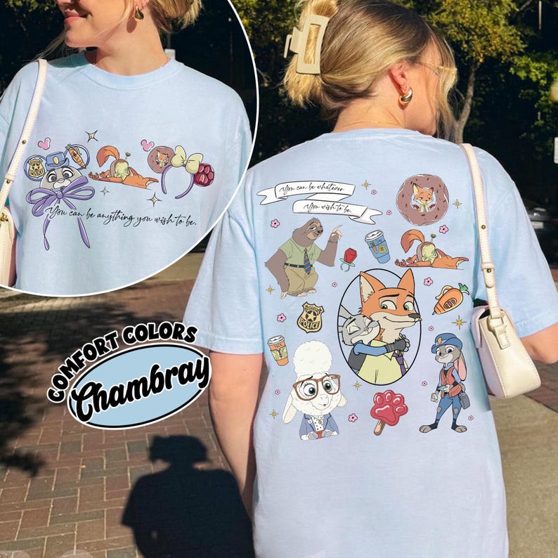 Puede incluir: Camiseta azul claro Comfort Colors Chambray con personajes de dibujos animados y el texto "You can be anything you wish to be." La camiseta presenta ilustraciones de un zorro, un conejo y otros personajes.