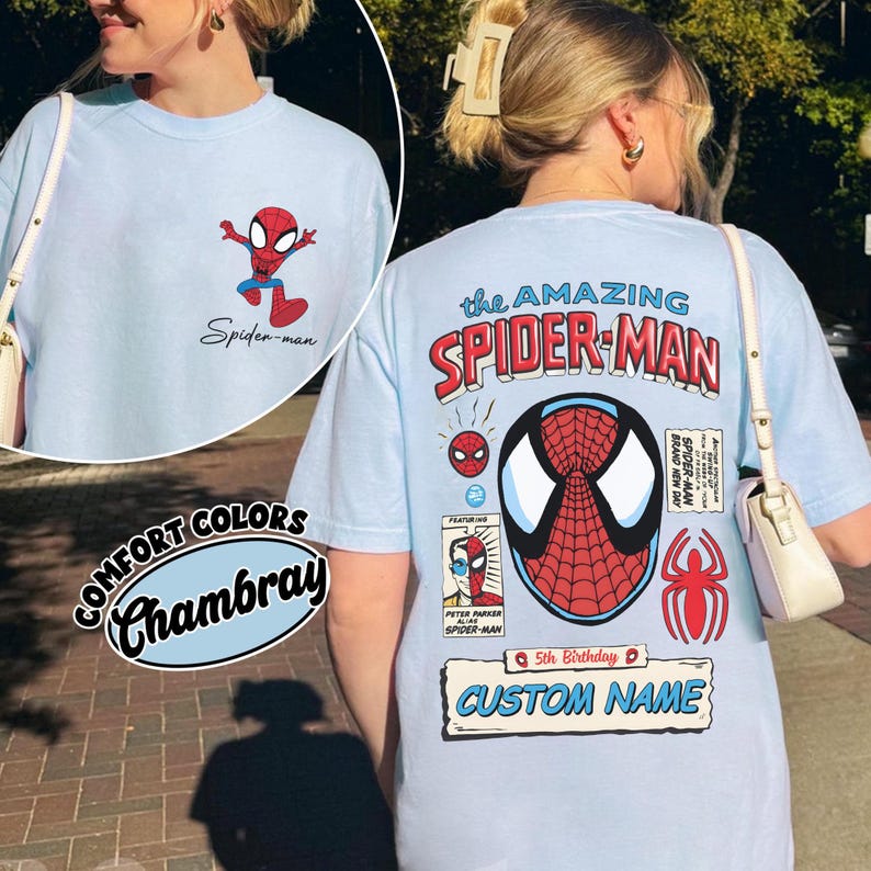 May include: Light blue t-shirt featuring Spider-Man graphics. The front has a small Spider-Man graphic and the text "Spider-man." The back displays "the AMAZING SPIDER-MAN" with a large Spider-Man mask design, additional graphics, and the text "CUSTOM NAME."