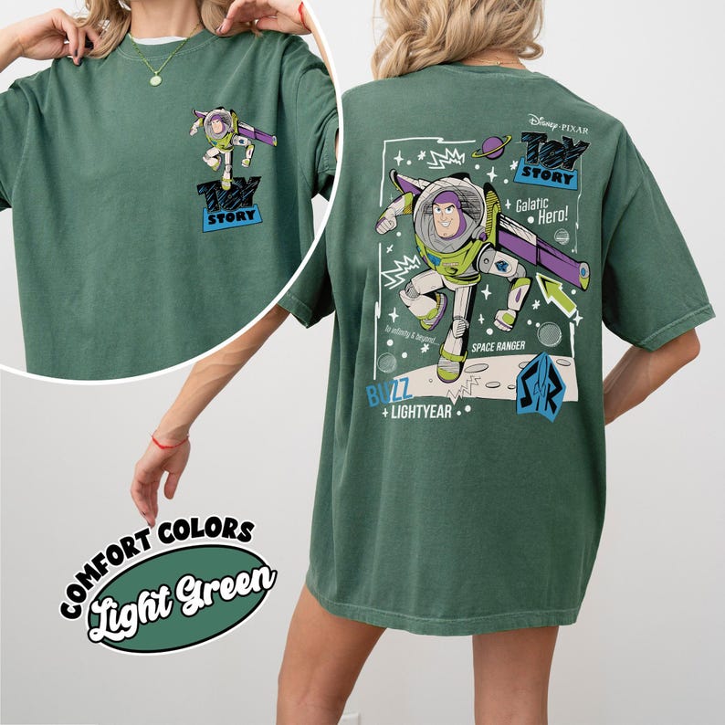 K&ouml;nnte beinhalten: Hellgr&uuml;nes T-Shirt mit Buzz Lightyear aus Toy Story. Die Vorderseite hat eine kleine Grafik, w&auml;hrend die R&uuml;ckseite ein gr&ouml;&szlig;eres Design mit dem Text "Toy Story", "Galactic Hero!" und "Space Ranger" zeigt. Das Shirt ist im Comfort-Colors-Stil.