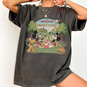May include: Dark gray t-shirt featuring a vintage-style graphic of Mickey Mouse, Minnie Mouse, and Pluto having a picnic. The graphic includes the text "Disney Mickey Mouse PERFECT PICNIC" in a circular design with a landscape background.