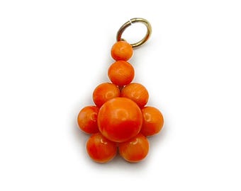 May include: A pendant featuring a cluster of smooth, round, orange beads arranged in a flower-like shape, topped with a smaller bead and a gold-toned metal jump ring. The beads vary slightly in size, with a larger central bead surrounded by smaller ones.