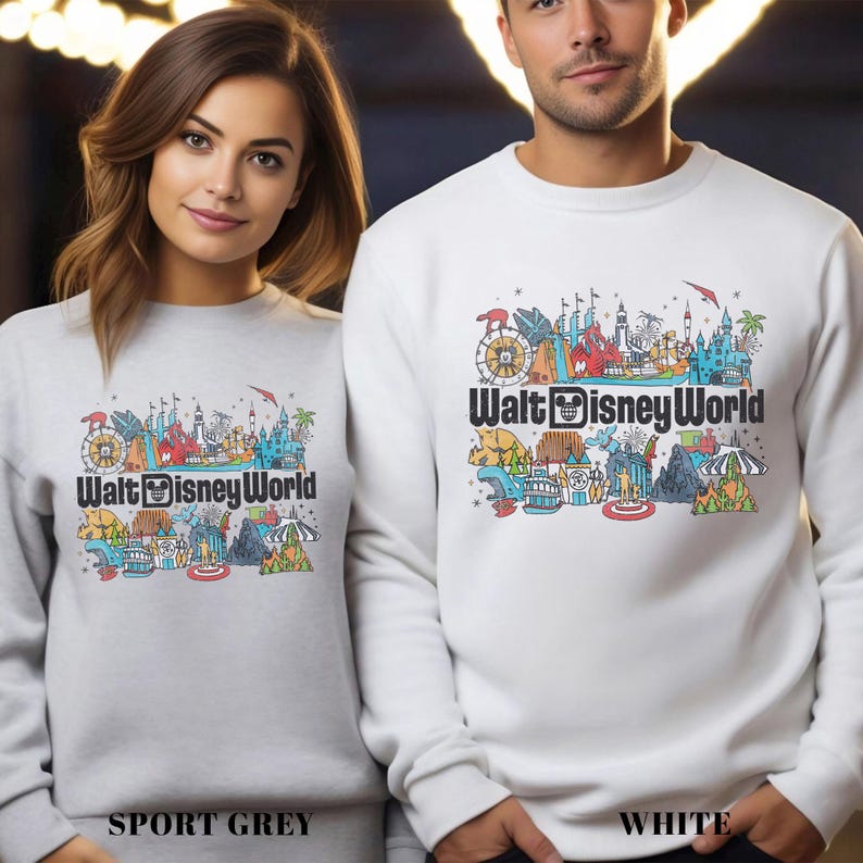 Puede incluir: Sudaderas grises deportivas y blancas con un gr&aacute;fico colorido de Walt Disney World. El gr&aacute;fico incluye una noria, un castillo y otros iconos del parque. El texto "Walt Disney World" est&aacute; impreso debajo.