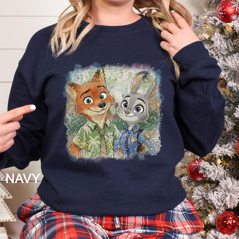 May include: Navy blue sweatshirt with a colourful graphic of Nick Wilde and Judy Hopps from Zootopia. The image shows the characters smiling, with Nick in a Hawaiian shirt and Judy in a police uniform. The word "NAVY" is printed on the bottom left.