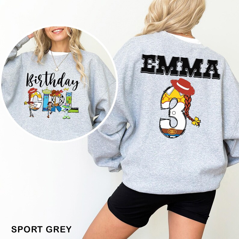May include: A light gray sweatshirt with the text "Birthday Girl" and cartoon characters on the front. The back features the name "EMMA" and a number "3" with a cowgirl hat and braid design. The sweatshirt is labeled "SPORT GREY".