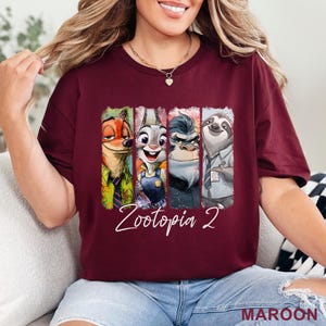 Peut inclure: T-shirt bordeaux avec des personnages de Zootopie 2. Le design comprend Nick Wilde, Judy Hopps, un gorille et Flash le paresseux, avec le texte "Zootopia 2" en &eacute;criture blanche. Le mot "MAROON" est imprim&eacute; en bas &agrave; droite.