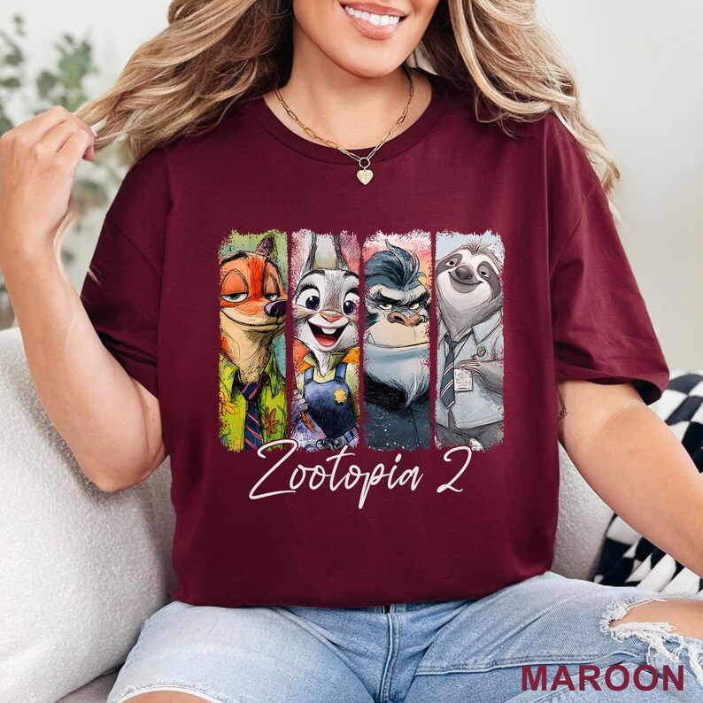 Peut inclure: T-shirt bordeaux avec des personnages de Zootopie 2. Le design comprend Nick Wilde, Judy Hopps, un gorille et Flash le paresseux, avec le texte "Zootopia 2" en &eacute;criture blanche. Le mot "MAROON" est imprim&eacute; en bas &agrave; droite.