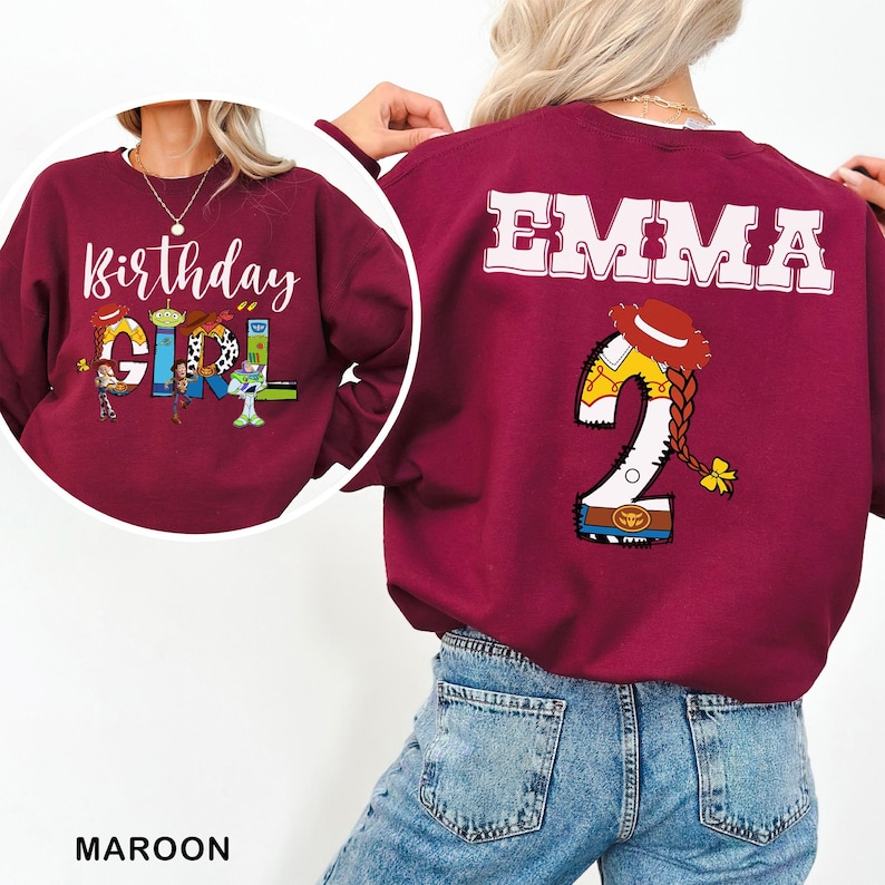 May include: Maroon sweatshirt with the text "Birthday Girl" and Toy Story characters. The back of the sweatshirt has the name "EMMA" and a number "2" with a cowgirl design. The word "MAROON" is at the bottom.