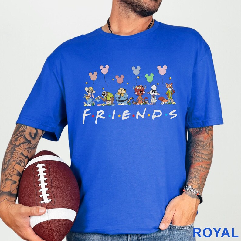 May include: Royal blue t-shirt with a cartoon design featuring characters and Mickey Mouse-shaped balloons. The word "FRIENDS" is printed in white. The shirt is a crew neck style.