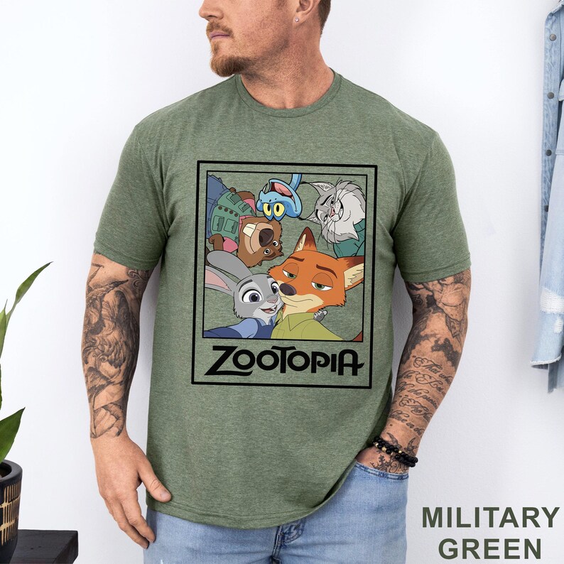 Peut inclure: T-shirt vert militaire avec un motif rectangulaire repr&eacute;sentant des personnages du film d'animation Zootopie. Le motif comprend Judy Hopps, Nick Wilde et d'autres personnages. Le mot "Zootopia" est imprim&eacute; en gras.