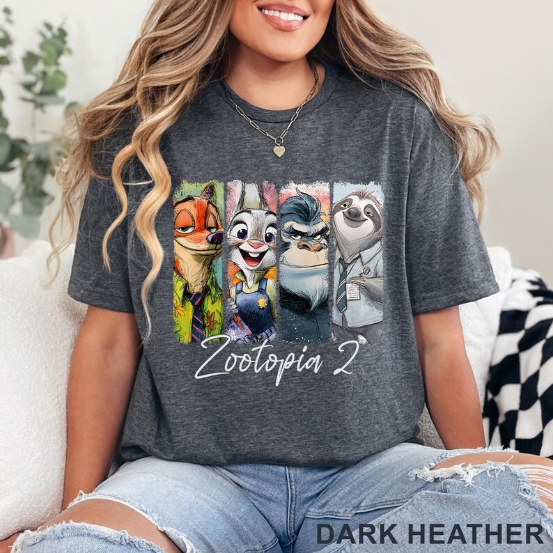 Peut inclure: T-shirt gris fonc&eacute; avec des personnages de Zootopie. Le graphisme comprend Nick Wilde, Judy Hopps, un gorille et Flash le paresseux. Le texte "Zootopia 2" est &eacute;crit en blanc. Le bas du t-shirt indique "DARK HEATHER".