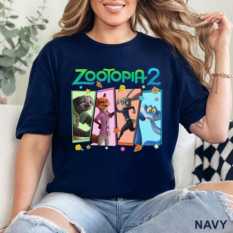 May include: Navy blue t-shirt with the text "Zootopia 2" in green and images of characters from the film in colourful rectangular frames. The shirt has a crew neck and short sleeves. The word "NAVY" is printed at the bottom.
