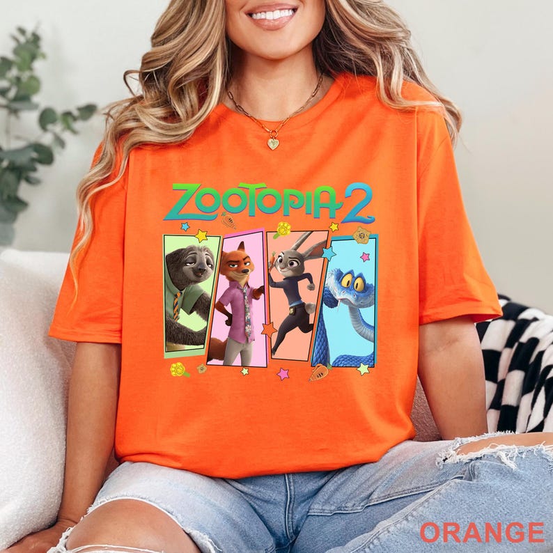 May include: Bright orange t-shirt with the words "ZOOTOPIA 2" above four cartoon character panels. The panels feature a sloth, fox, rabbit, and snake. The word "ORANGE" is printed at the bottom of the shirt.