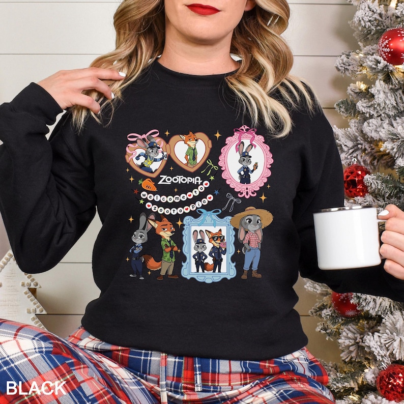 Pode incluir: Camisola preta de gola redonda com um gr&aacute;fico colorido de personagens do filme de anima&ccedil;&atilde;o Zootopia. O design inclui retratos emoldurados e imagens em forma de cora&ccedil;&atilde;o dos personagens, com a palavra "Zootopia" no centro.