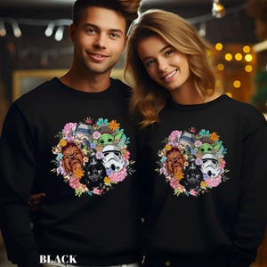 Puede incluir: Sudaderas negras con un dise&ntilde;o de corona floral con personajes de Star Wars como Darth Vader, Chewbacca y un Stormtrooper. La palabra "BLACK" est&aacute; impresa en la parte inferior.