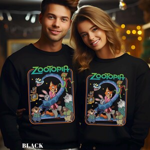 May include: Black sweatshirts featuring the word "Zootopia" in green and blue, with a colorful graphic of characters from the animated film. The sweatshirts are worn by a smiling couple.
