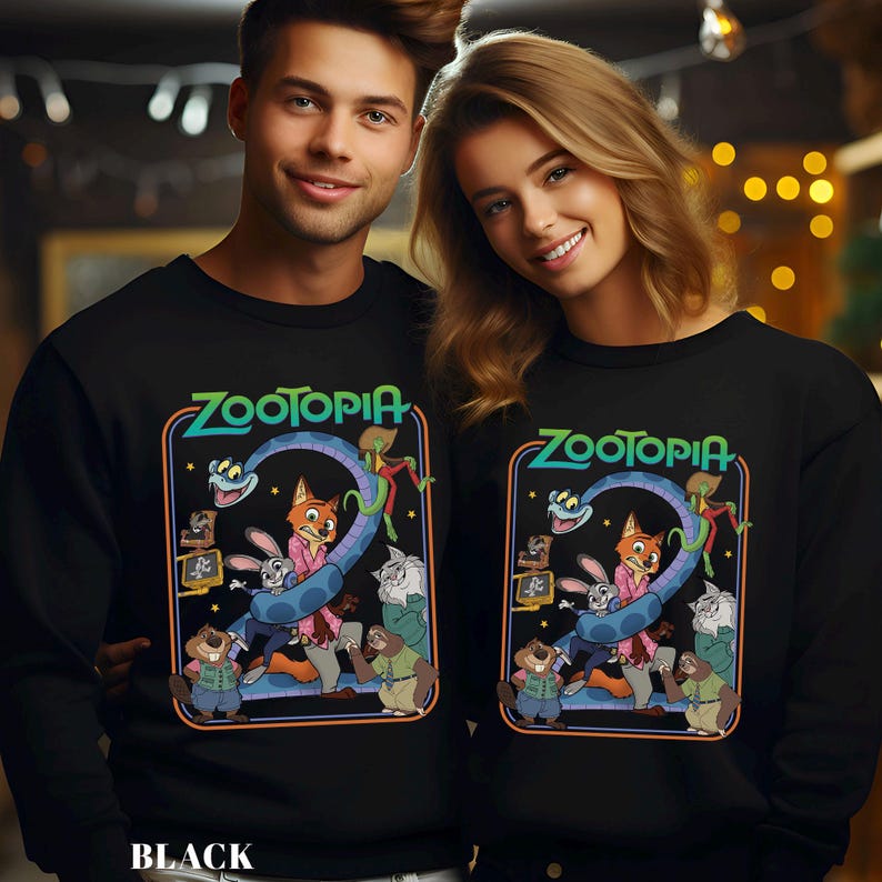 May include: Black sweatshirts featuring the word "Zootopia" in green and blue, with a colorful graphic of characters from the animated film. The sweatshirts are worn by a smiling couple.