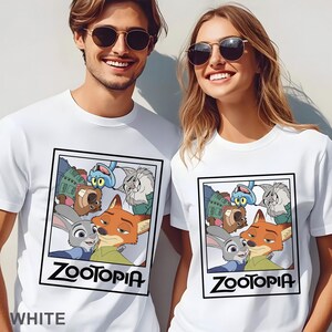 Peut inclure: T-shirts blancs avec un graphisme du film d'animation "Zootopie". Le motif comprend les personnages Judy Hopps, Nick Wilde et d'autres, encadr&eacute;s dans un cadre noir. Le mot "Zootopia" est imprim&eacute; en gras, en lettres noires sous l'image. Le mot "WHITE" est imprim&eacute; en bas.