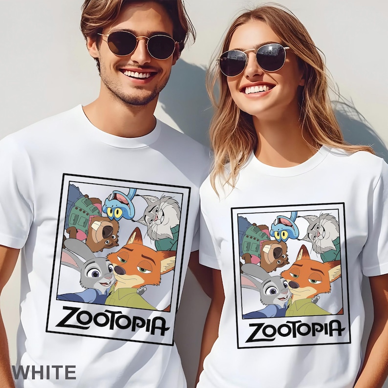 Peut inclure: T-shirts blancs avec un graphisme du film d'animation "Zootopie". Le motif comprend les personnages Judy Hopps, Nick Wilde et d'autres, encadr&eacute;s dans un cadre noir. Le mot "Zootopia" est imprim&eacute; en gras, en lettres noires sous l'image. Le mot "WHITE" est imprim&eacute; en bas.
