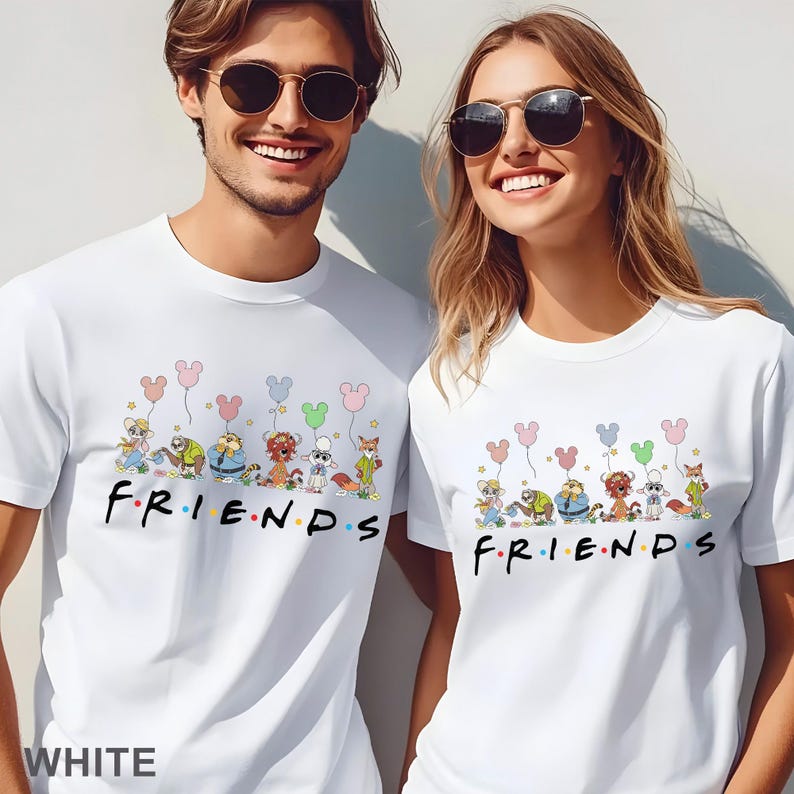 May include: White t-shirts with a cartoon design of characters holding Mickey Mouse-shaped balloons above the word "FRIENDS" in colourful letters. The shirts are worn by two people.
