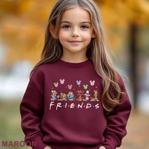 May include: Maroon sweatshirt featuring cartoon characters and the word "FRIENDS" in white letters. The sweatshirt has a crew neck and long sleeves. The design includes several cartoon characters and Mickey Mouse silhouettes.