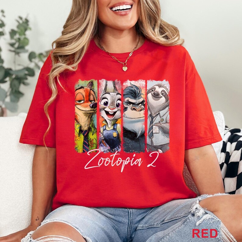 Peut inclure: T-shirt rouge avec un imprim&eacute; des personnages de Zootopia 2. Le graphisme comprend Nick Wilde, Judy Hopps, un gorille et Flash le paresseux. Les mots "Zootopia 2" sont &eacute;crits en blanc en dessous.
