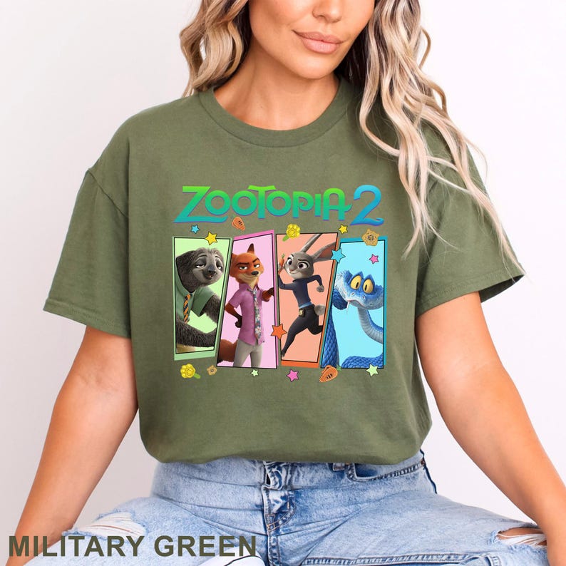 May include: Military green t-shirt with the text "ZOOTOPIA 2" and a graphic of characters from the animated film. The graphic features a sloth, fox, rabbit, and snake in colourful rectangular frames. The shirt is a solid colour.