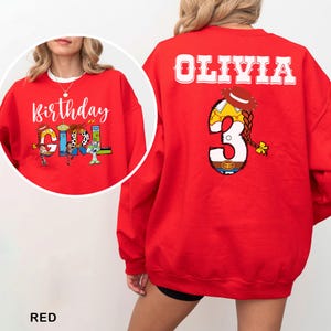 May include: A red sweatshirt with the text "Birthday Girl" on the front and "Olivia" and the number "3" on the back. The graphics feature characters from a popular animated movie. The sweatshirt is a vibrant red color.