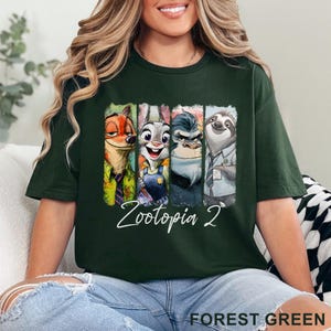 Peut inclure: T-shirt vert for&ecirc;t avec un graphisme color&eacute; des personnages de Zootopie : Nick Wilde, Judy Hopps, le chef Bogo et Flash. Le design comprend le texte "Zootopia 2" en &eacute;criture cursive. Le t-shirt est confortable.