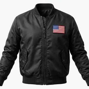 Pode incluir: Um blusão bomber preto com gola, punhos e bainha canelados, um fecho de correr frontal a todo o comprimento e um emblema retangular da bandeira dos Estados Unidos posicionado na parte superior esquerda do peito.