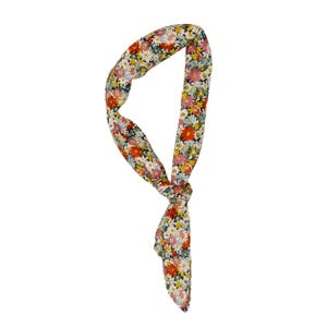 May include: A long, thin fabric hair accessory tied in a knot, featuring a dense, colorful floral pattern with red, pink, white, yellow, and light blue flowers set against a dark background. The accessory has a tapered shape and a smooth texture.