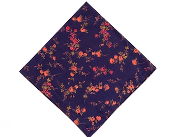 Può includere: Un fazzoletto quadrato blu navy con un motivo floreale. Il design presenta rose arancioni e rosse con foglie e steli verdi. Il fazzoletto è realizzato in un tessuto morbido ed è piegato a forma di diamante.