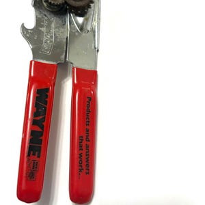 May include: A vintage can opener with red handles and a silver metal body. The handle on the left is labeled "WAYNE" in white text. The other handle has the text "Products and answers that work..."