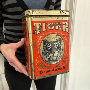 May include: Vintage rectangular tin with a red and gold design. The tin features the words "BRIGHT TIGER" and a tiger illustration. Text on the tin reads "CHEWING TOBACCO 5 CENT PACKAGES". The tin has a worn, antique appearance.