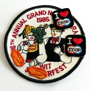 May include: A vintage patch and two smaller patches. The large, circular patch features a cartoon couple and the text "16th Annual Grand N. Wit Surferfest 1985." The smaller patches say "I ❤️ COOP" with a red heart.