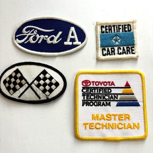 May include: Four embroidered patches. One is an oval with "Ford A" in white on a blue background. Another is a square with "Certified Car Care" and a star emblem. A third patch has checkered flags. The last is a Toyota Master Technician patch.