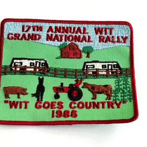 May include: Embroidered patch with a green background featuring a red barn, two travel trailers, and various farm animals. The text reads "17th Annual WIT Grand National Rally" and "WIT GOES COUNTRY 1986."