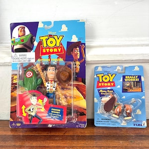 Peut inclure: Deux figurines Toy Story vintage dans leur emballage d'origine. L'une repr&eacute;sente Woody avec un poing perforant, l'autre un porte-cl&eacute;s Slinky Dog. L'emballage comprend le logo Disney Toy Story et des &eacute;tiquettes d'avertissement.